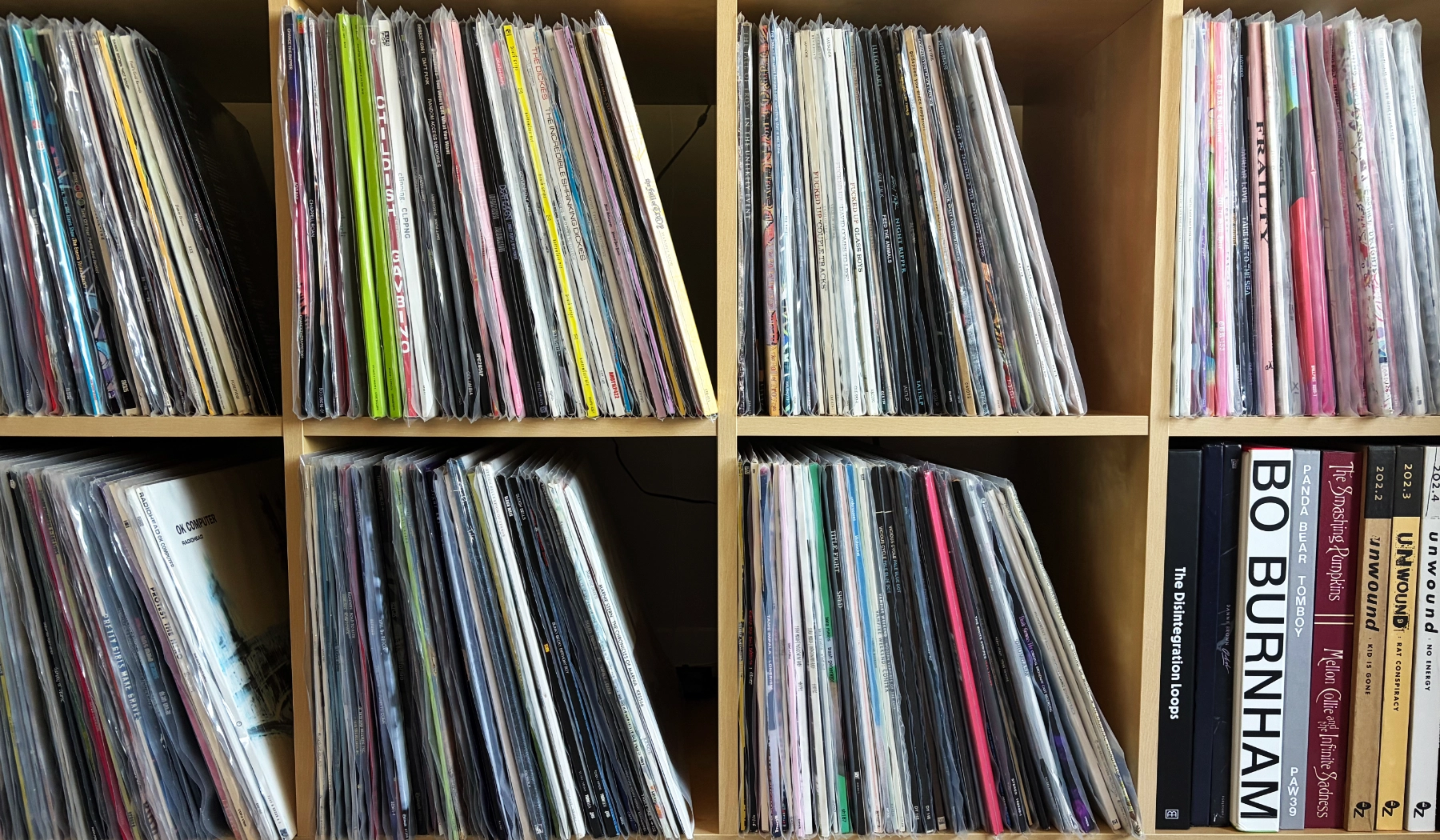 A bunch of vinyl records vertically stacked on a shelf.